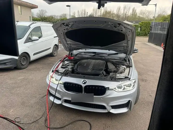 BMW 3 Series with the bonnet open, connected to the van on a driveway