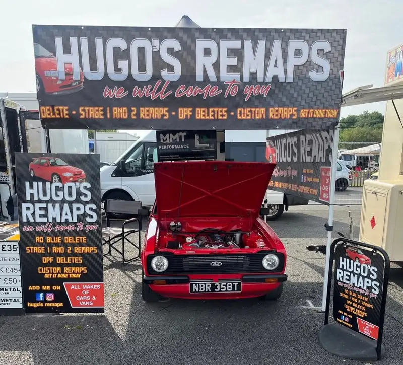 Hugo's Remaps stand at a car show with a red Ford Escort and banners
