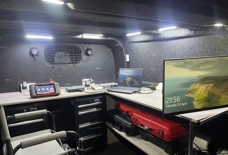 The van workbench lit at night with a diagnostic scanner and laptop