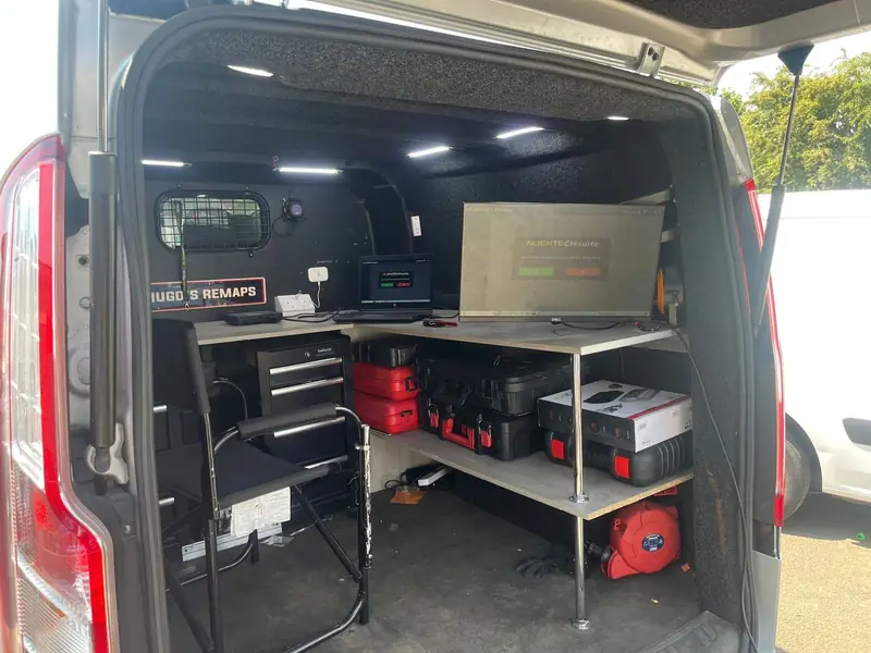 Inside the Hugo's Remaps van: a workbench with a laptop and a screen running Alientech software